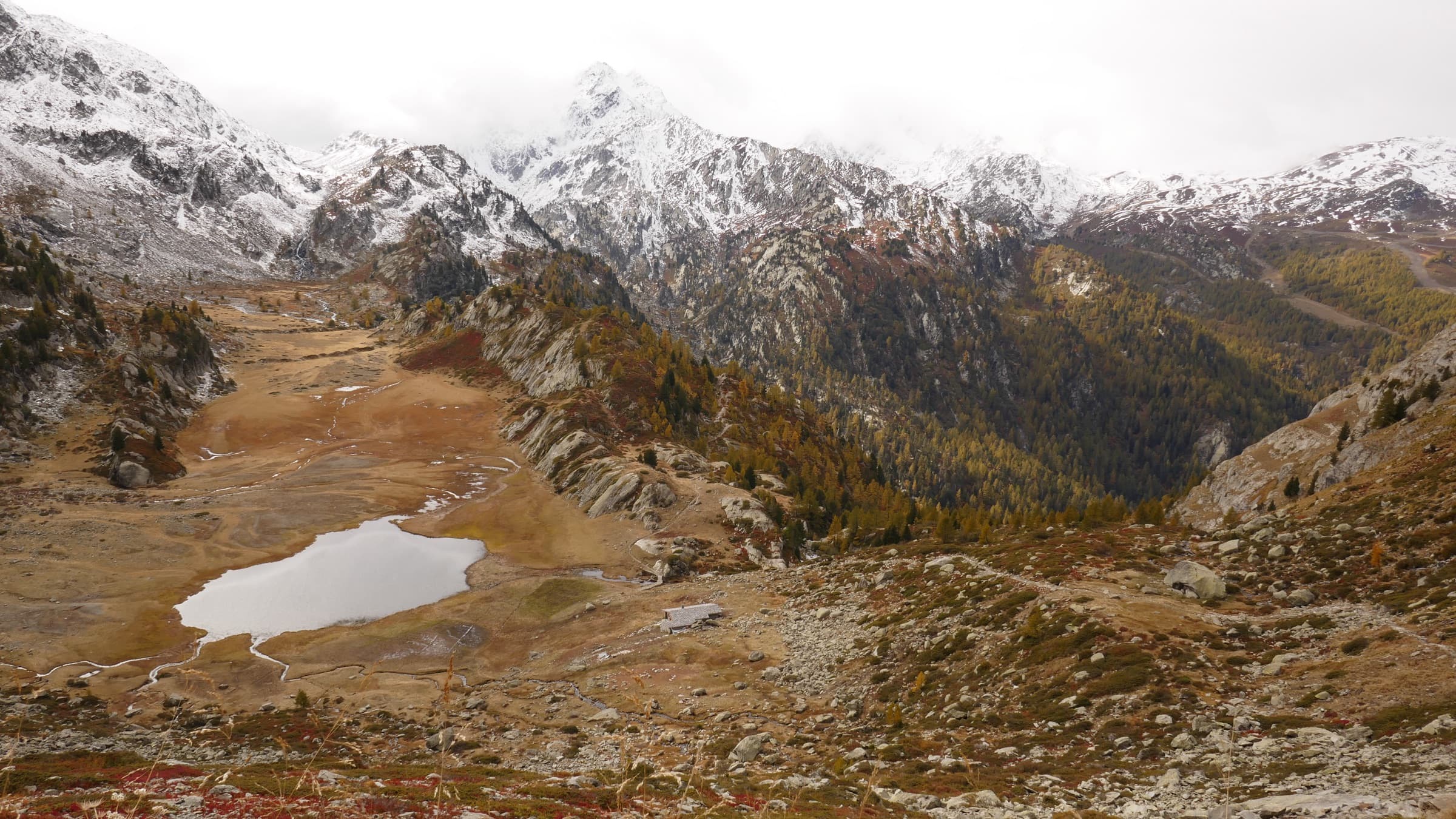 Rust-orange larches and small lakes below freshly snowed peaks