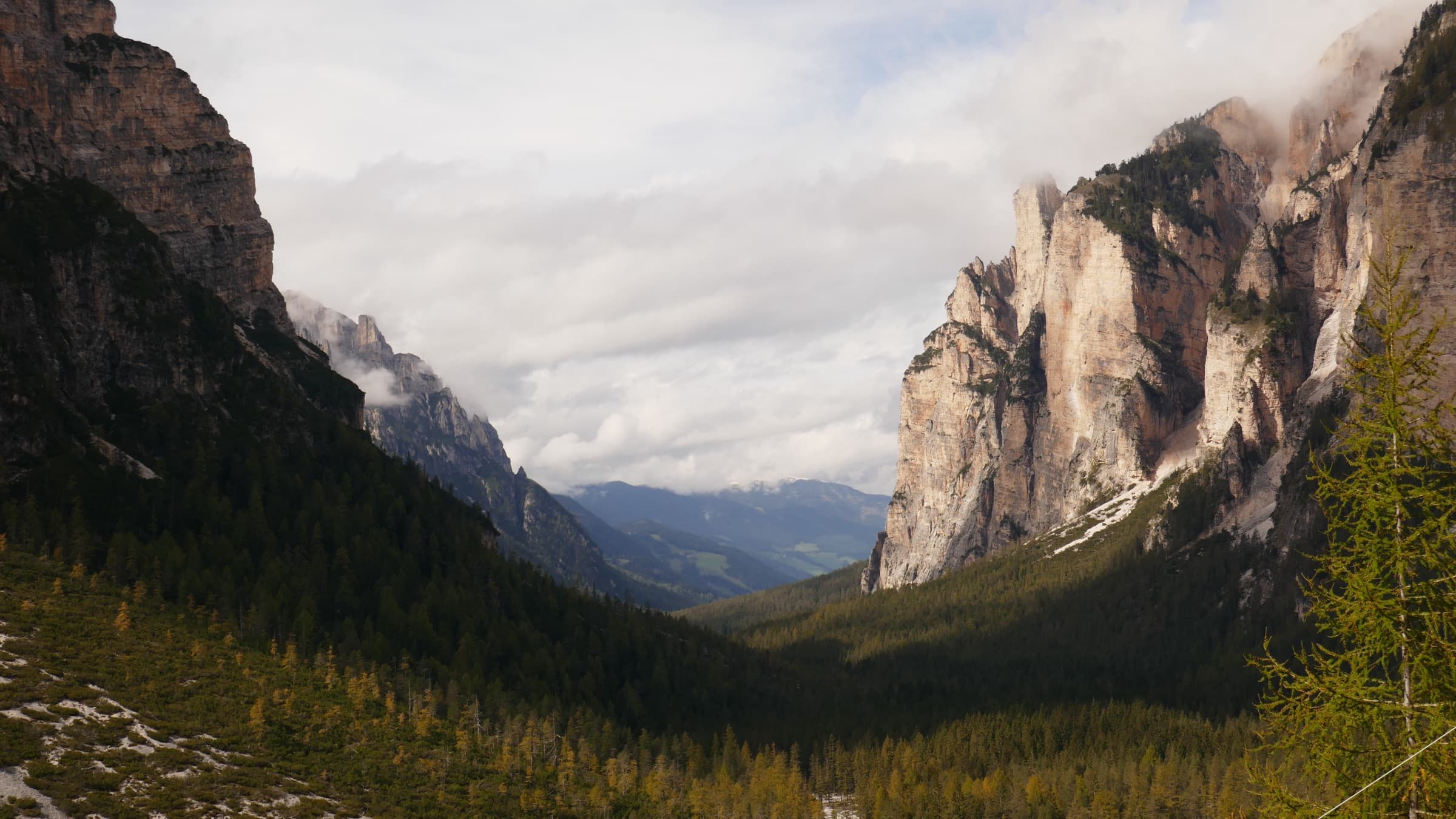 A forested Italian valley flanked left and right by huge pale rock walls