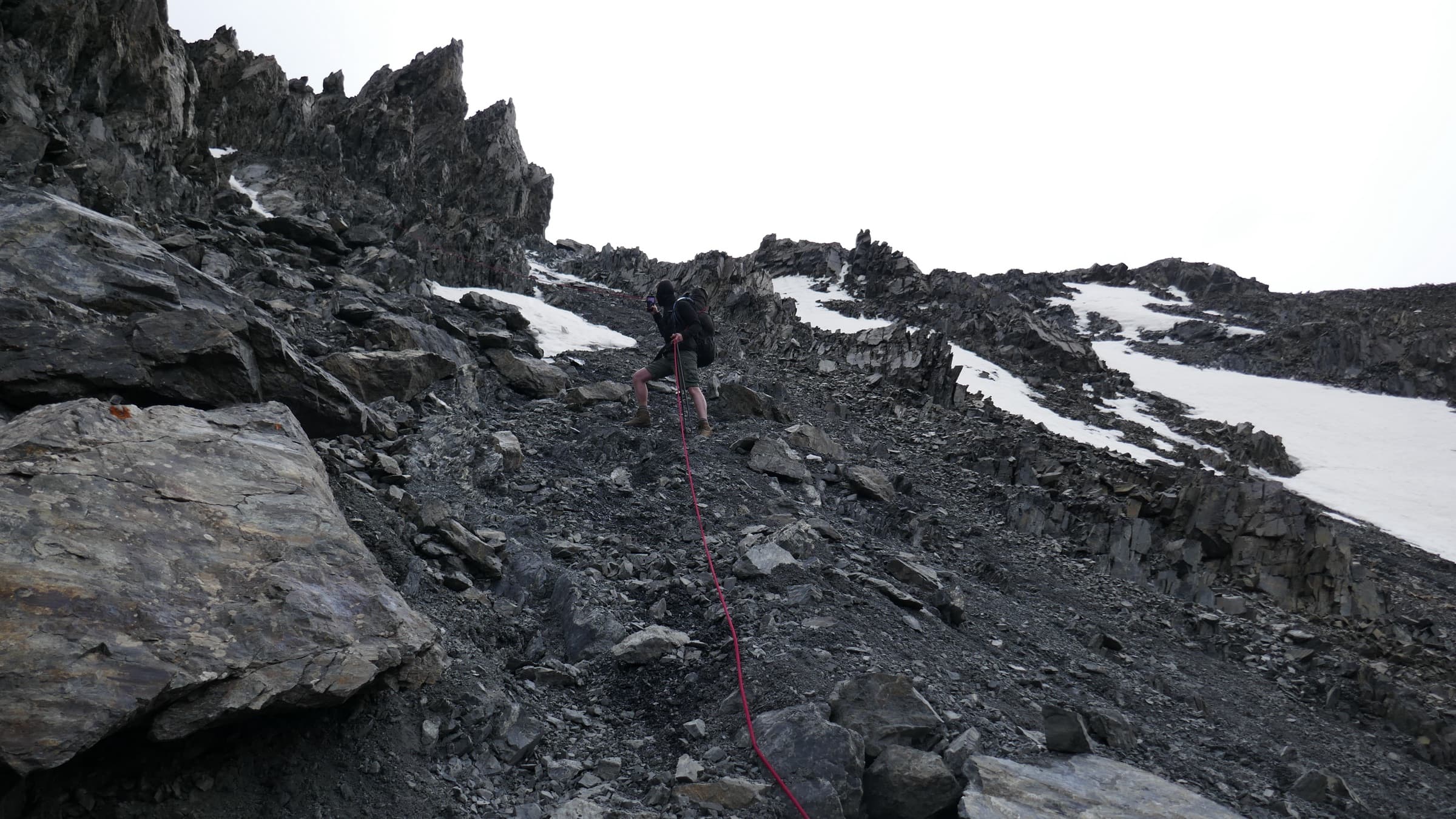 A climber picking through dark scree below the col