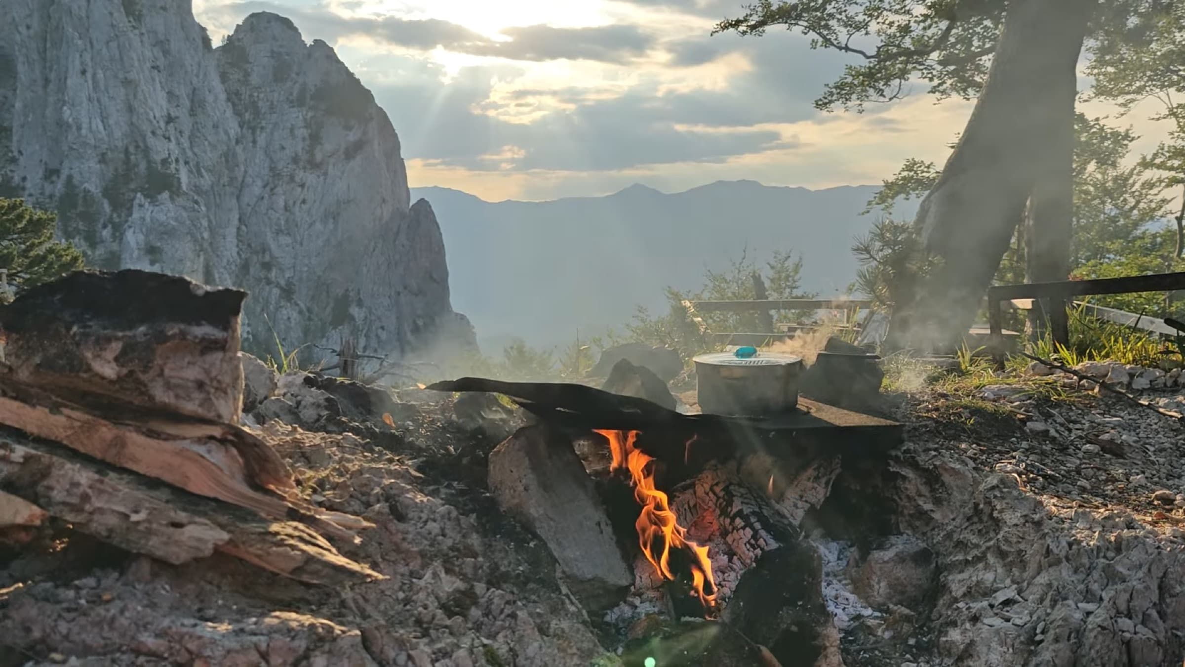 A campfire burning at dusk with mountains behind