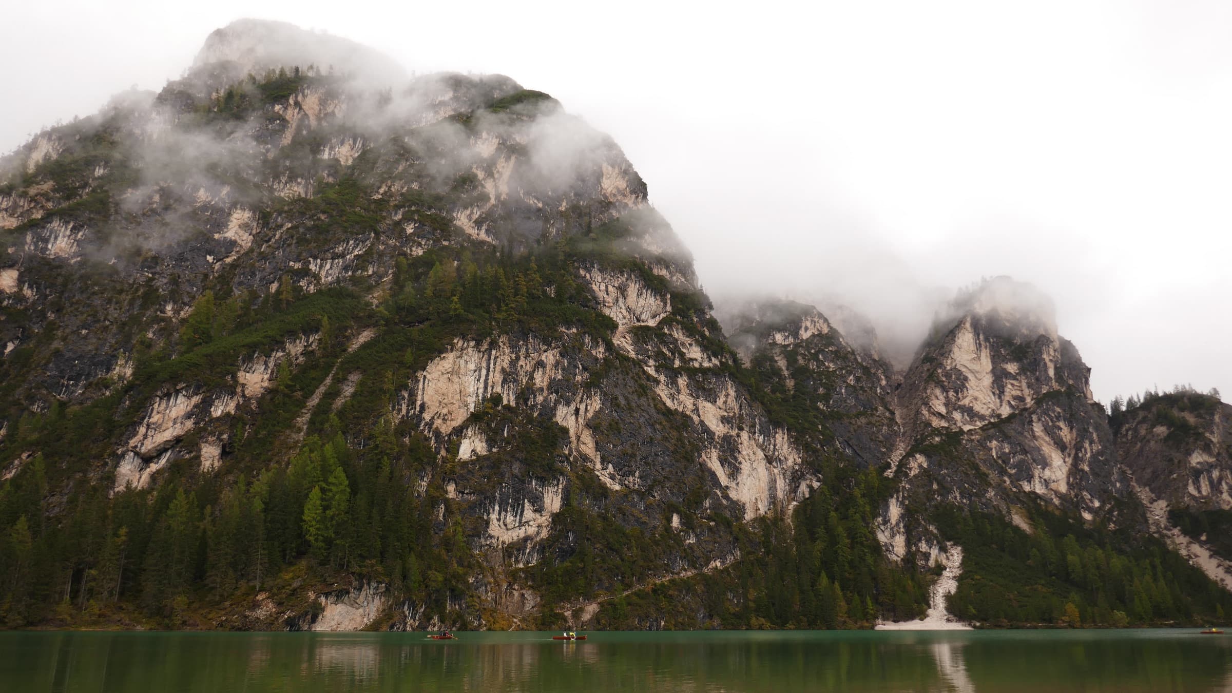 Cloud sinking over a pale rock face above a dark alpine lake