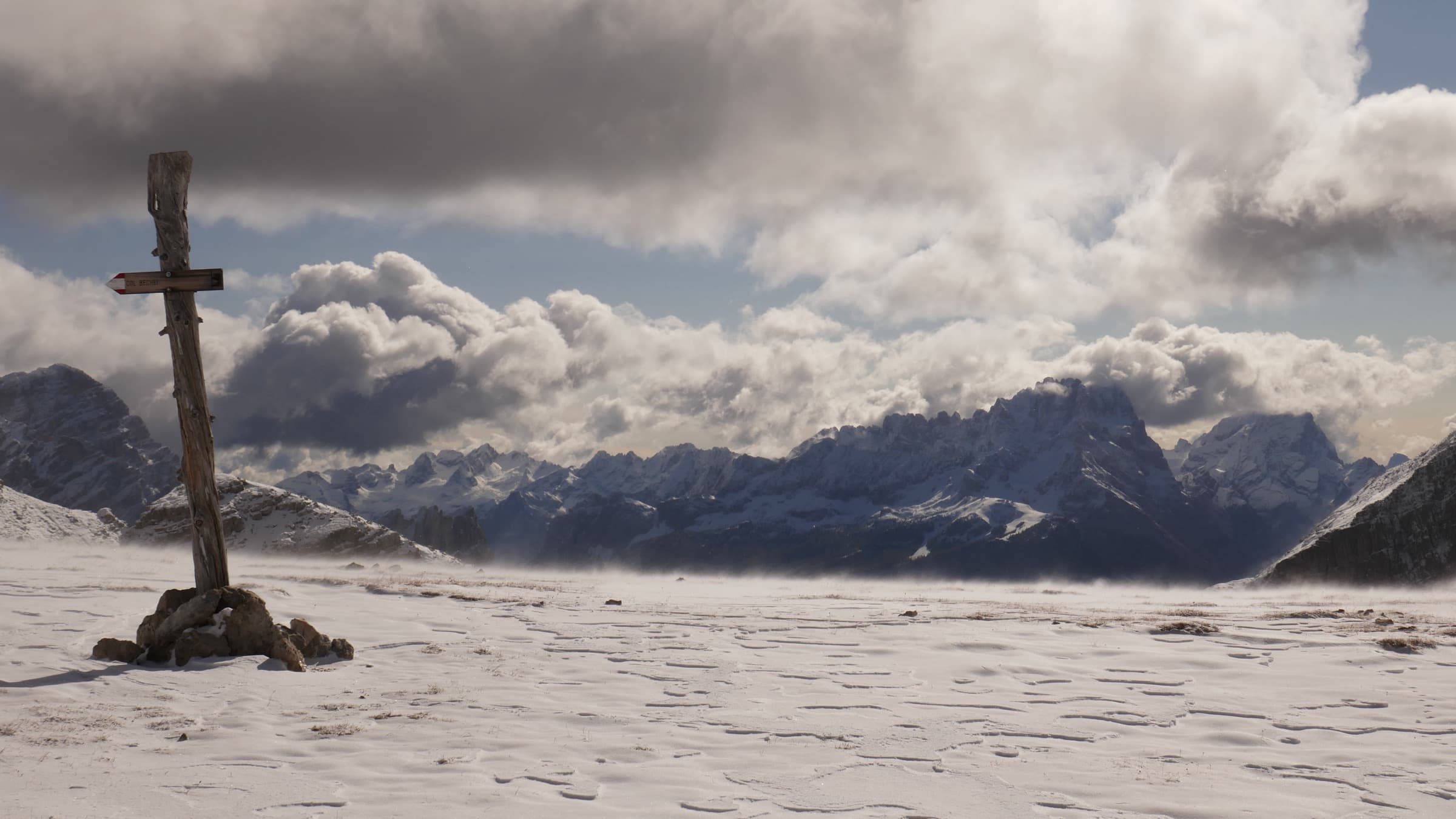 A wooden summit cross standing in snow and cloud