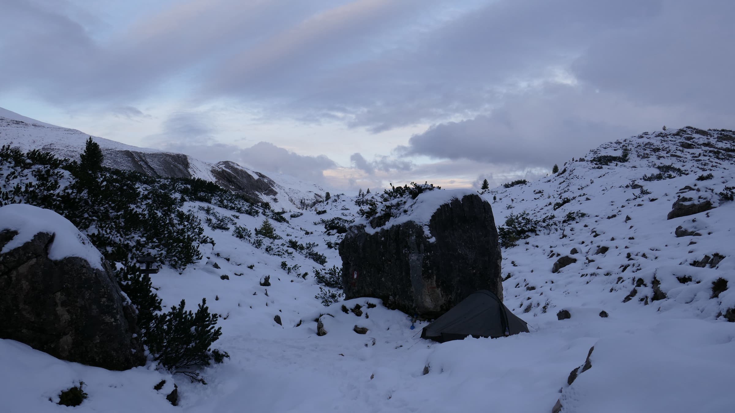 Fresh snow dusting dark boulders on a high col