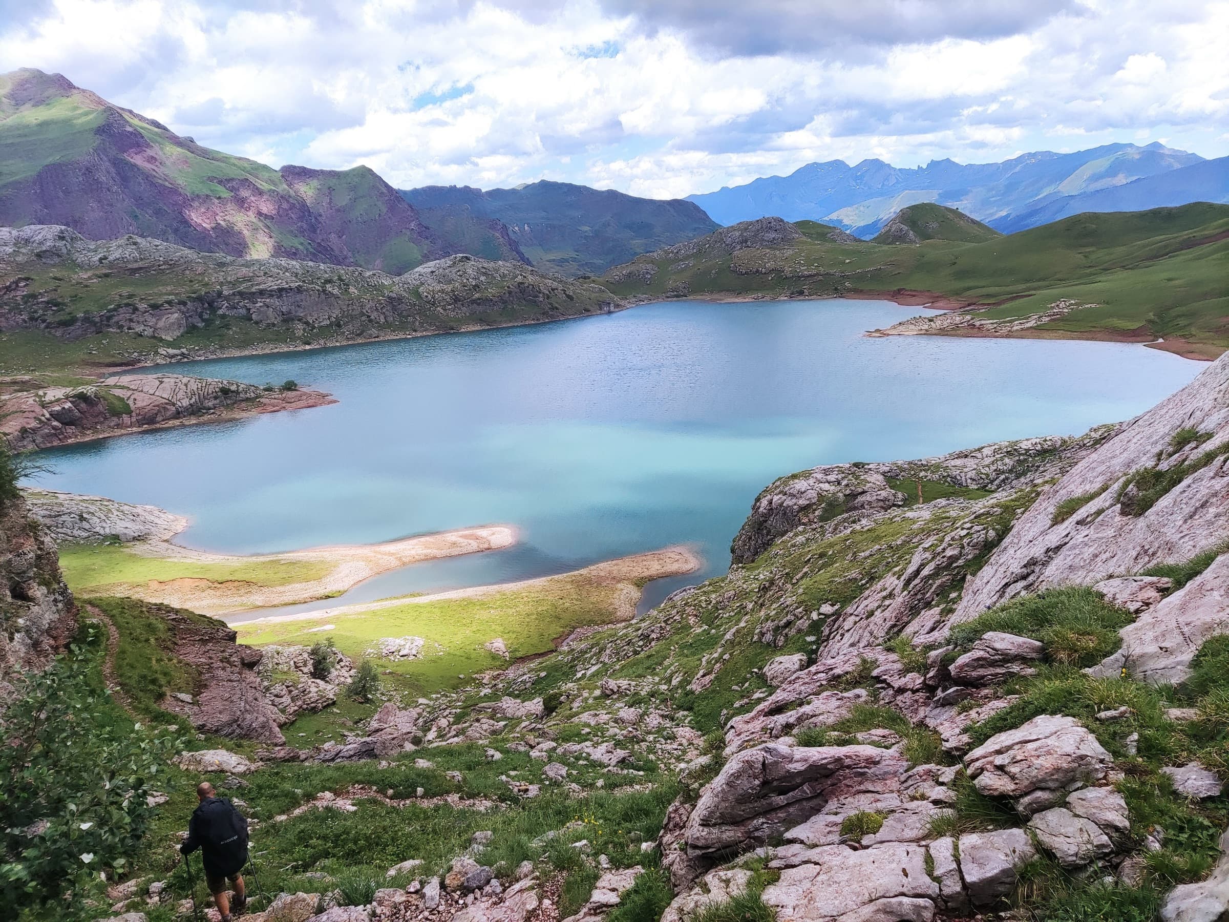 A turquoise glacial lake ringed by pale rock and green shores
