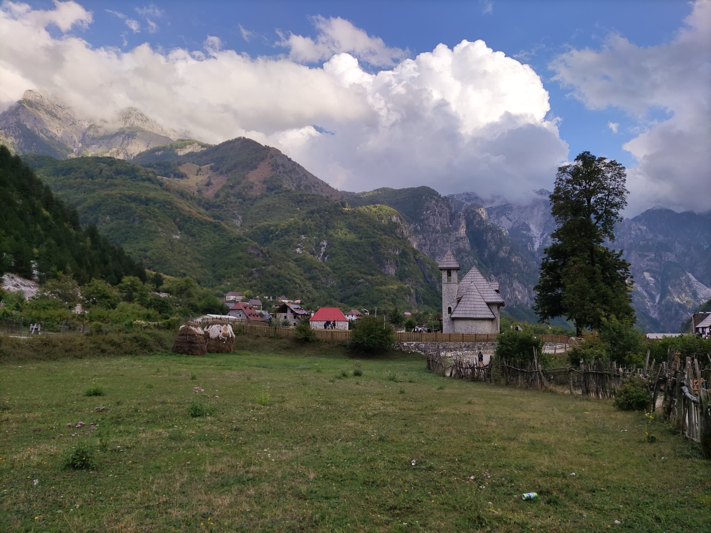 A stone church with a shingled roof in a mountain meadow