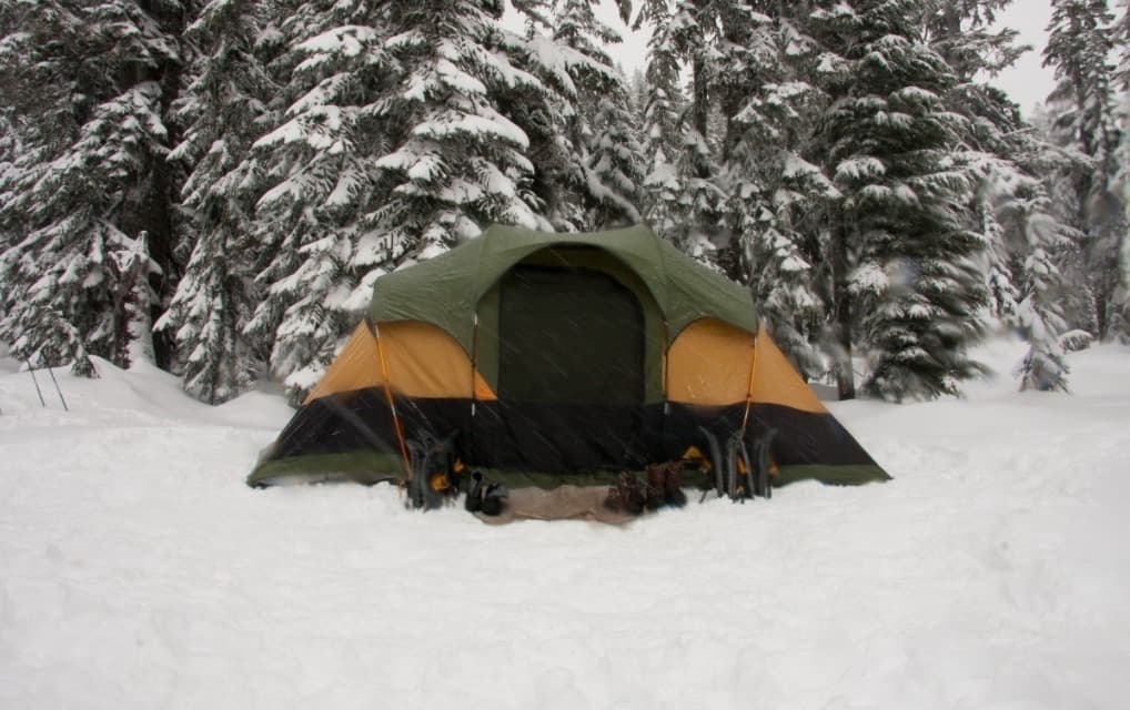 Ultralight 4-season tent pitched in snow with mountains in background