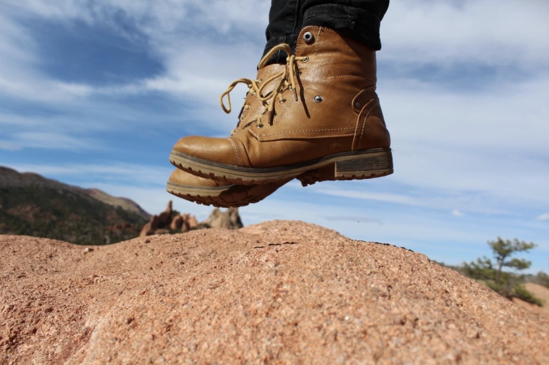 Well-worn full-grain leather hiking boots on a rocky mountain trail