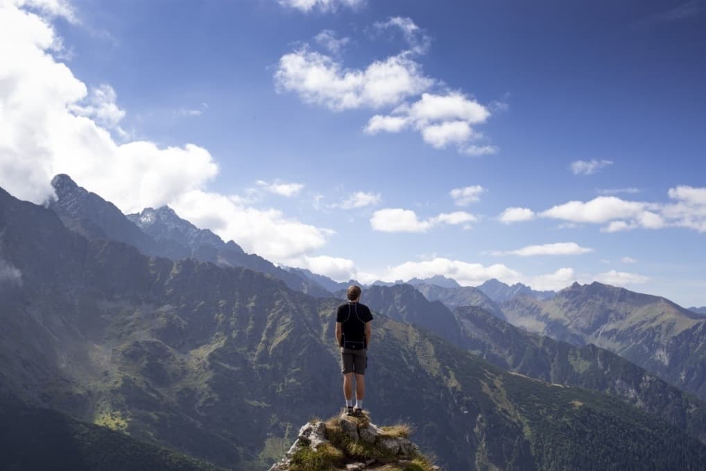 Hiker wearing a grey merino wool hiking shirt on a mountain trail